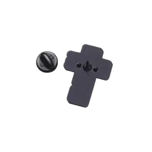Détail du revers d'une broche en forme de croix noire avec fermoir papillon en métal