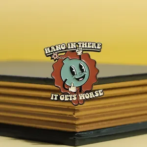 Macro shot of retro enamel pin with funny cartoon bomb on a vintage book spine