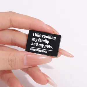 Gros plan de la broche rectangulaire noire avec citation humoristique sur fond blanc