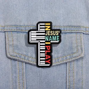 Détail d'une broche croix émaillée avec touches de piano sur une veste en jean
