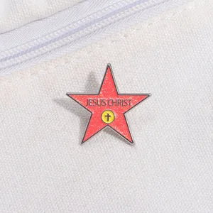 Macro detail of red glitter enamel star brooch with Jesus Christ text and cross logo