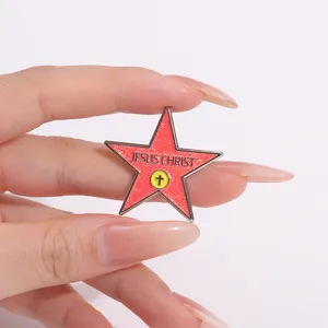 Detailed shot of red glitter star enamel pin featuring Jesus Christ text and cross
