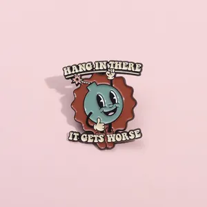 Detailed close-up of cartoon enamel pin with Hang In There text and bomb character