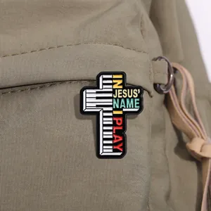 Détail d'un pin's en émail en forme de croix avec touches de piano sur sac à dos