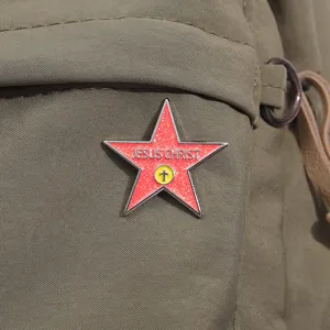 Detail of red glitter pentagram Jesus Christ badge pinned on green canvas bag