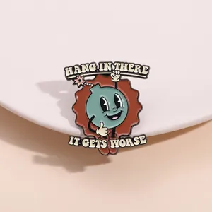 Enamel bomb pin with ironic text Hang In There It Gets Worse on beige background