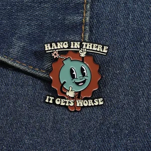 Close-up of retro enamel bomb pin on denim with text Hang in There It Gets Worse