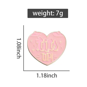 Detail of pink heart enamel pin with Tits Up text and dimensions of 1.18 by 1.08 inches