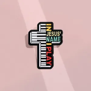 Détail de la broche croix en émail avec touches de piano et texte In Jesus Name I Play