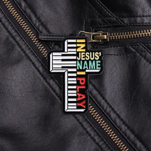 Détail d'une broche en croix émaillée avec touches de piano et texte chrétien