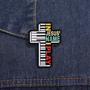 Détail macro de la broche croix en émail avec touches de piano et texte religieux