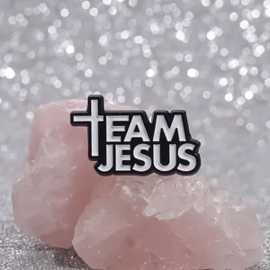 Close-up of Team Jesus enamel pin with black background and white cross on sequins
