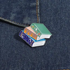 Detail of stacked fantasy book enamel pins on denim jacket for reading lovers