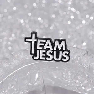 Macro shot of Team Jesus enamel pin with white cross on glittery silver background
