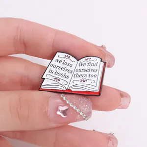 Macro view of an enamel book pin featuring motivational quotes and pink floral details