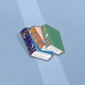 Close-up of stack of fantasy book enamel pins with celestial moon and floral patterns