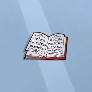 Cartoon enamel book pin with motivational quote on white pages and red cover