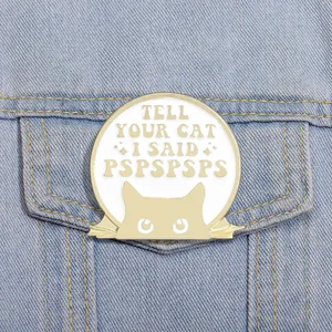 Close-up of cat enamel pin with funny quote on a blue denim jacket pocket