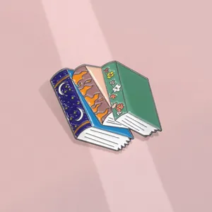 Detailed view of stacked enamel book pins with celestial patterns and nature themes