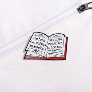 Detail of open book enamel pin with inspirational quote on white canvas fabric