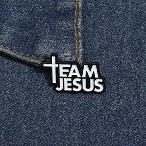Detailed view of Team Jesus enamel pin with white cross on dark blue denim fabric
