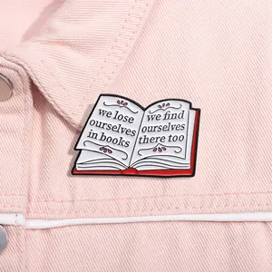 Macro shot of an open book enamel pin with literary quote on a pink denim jacket
