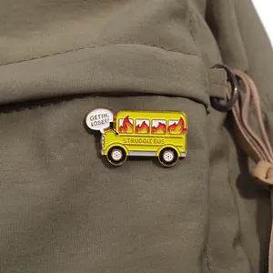 Detail of a yellow Struggle Bus enamel pin with flames on a green canvas background