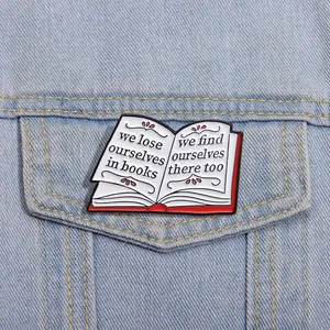 Detail of red enamel book pin with literary quote on a blue denim jacket pocket