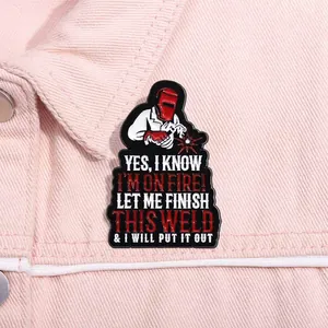 Détail d'un pin's en émail avec un soudeur rigolo et texte sur un fond en jean rose