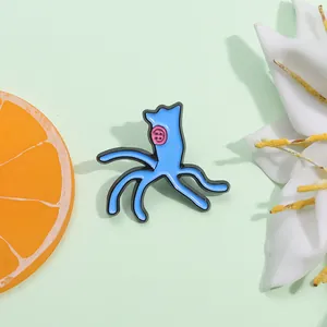 Detail of blue Scrump enamel pin with pink button eyes on light green background