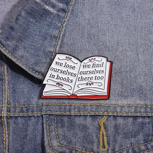Close-up of an enamel book brooch with inspirational text on a blue denim jacket texture