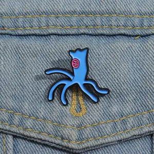 Blue enamel art brooch with pink button eye pinned on light blue denim jacket pocket