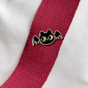 Détail d'un pin's en émail dragon noir avec ailes de chauve-souris sur sangle rouge