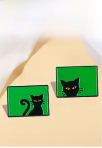 Détail de deux épingles rectangulaires en émail vert avec motifs de chats noirs