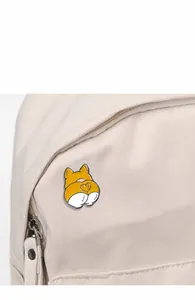 Close-up of a cute cartoon corgi butt enamel pin attached to a white canvas backpack