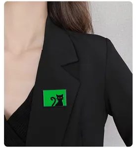 Vue détaillée d'une broche chat rectangulaire verte sur un revers noir