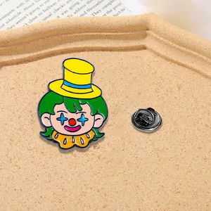 Cute cartoon clown enamel pin with yellow hat and green hair on a textured display tray