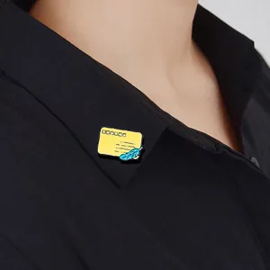 Detail view of a yellow enamel envelope brooch with blue feather on a black shirt collar