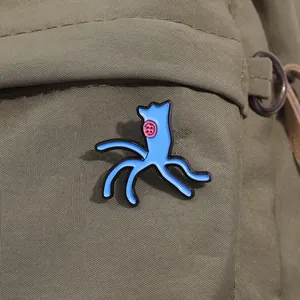 Detail of blue phage enamel pin with pink button eye on an olive green canvas bag