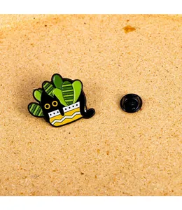 Macro detail of enamel cat cactus brooch pin with black butterfly clasp on cork