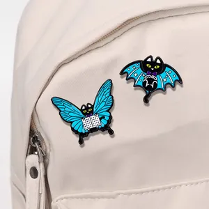 Cartoon black cat enamel pins with butterfly and bat wings on a canvas bag