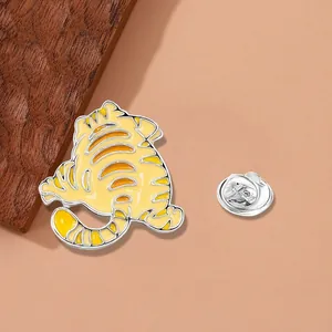 Detailed view of a cute tiger enamel pin with a silver butterfly clutch on wood