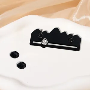 Black metal mountain brooch featuring a sliding pin mechanism and rubber clutch backings