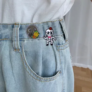 Détail de pins en émail avec motifs de crâne et fleurs sur tissu en jean denim