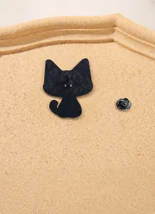 Detail of black cat enamel pin showing back pin structure and textured metal finish