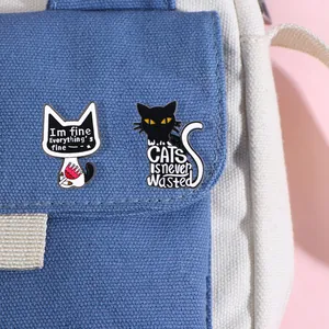 Detail of two cartoon cat enamel pins with witty text on blue canvas fabric