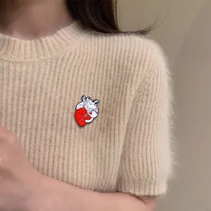 Creative enamel heart pin with white cats displayed on a light beige knitted sweater
