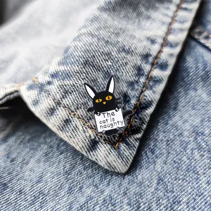 Cartoon black cat enamel pin with The cat is naughty sign on denim jacket lapel
