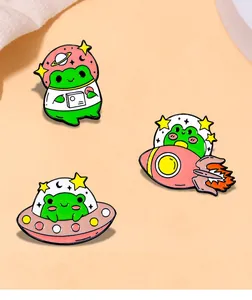 Detailed view of three cute frog astronaut enamel pins with rocket and UFO metal designs