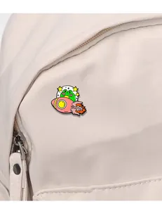 Detail of cartoon frog in rocket enamel pin attached to a cream canvas backpack